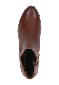 Bota de cuero marrón hasta el tobillo con acabado suave, puntera redondeada y cremallera lateral. Acabado textil suave en el borde superior. Nombre de la marca visible en el interior.
