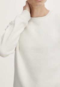Witte crewneck sweatshirt van zacht materiaal. Bevat een subtiele "blend" logo in bijpassende kleur. Lange mouwen met ribgebreide boorden.