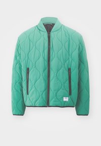 Quilted bomberjakke i lys grøn med høj krave, front lynlås og to sidelommer med lynlås. Struktureret bølgemønster over hele jakken.