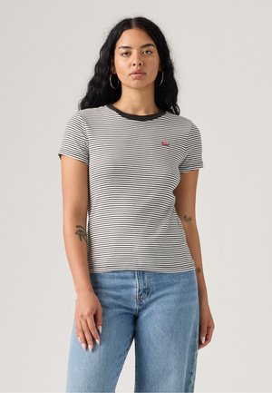 Stripet kortermet T-skjorte i svart og hvitt, med rund hals og liten rød logo-patch. Sammen med lyseblå jeans.