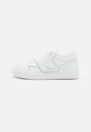 Helemaal witte lage sneaker met geperforeerde neus, een grote zijband en gestikte details op een witte achtergrond.