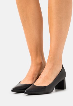 Escarpins en cuir noir à bout pointu, avec un talon moyen et un fini lisse. Design simple sans matériel ni motifs visibles.