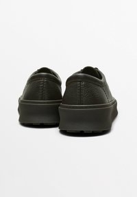 Baskets en cuir marron foncé avec une texture lisse, un design arrondi et une semelle en caoutchouc épaisse. Présente des détails de couture minimalistes à l'arrière.