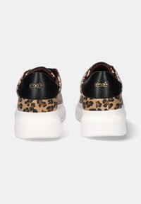 Zapatillas con estampado de leopardo, con un capuchón negro en el talón, suela gruesa blanca y marca dorada en la parte trasera. Superior texturizado con un acabado suave.