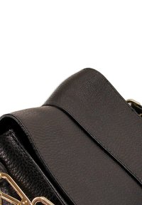 Zwarte leren handtas met textuurafwerking, voorzien van een gladde klep, gouden hardware en een opvallende schouderband.