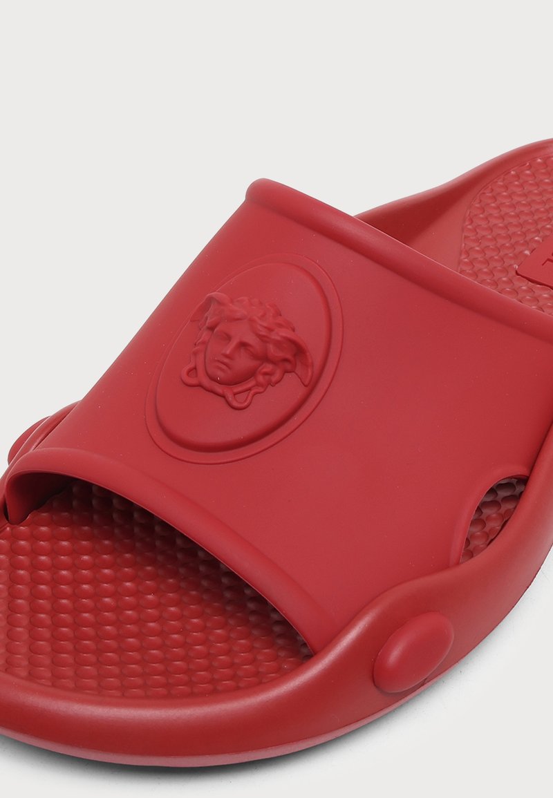 Roter Gummi-Slipper mit strukturierter Innensohle und geprägt Medusa-Kopf-Logo auf dem Riemen.