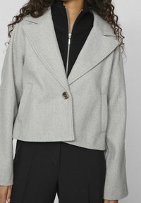 Šedá zkrácená bunda s klopovým límcem, zapínáním na jeden knoflík a dvěma bočními kapsami. Vyrobena z měkké, strukturované tkaniny.