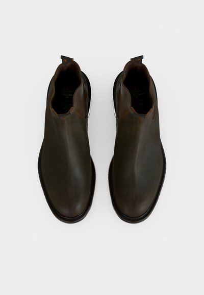 Ζευγάρι σκούρα καφέ δερμάτινα ankle boots χωρίς κορδόνια με στρογγυλεμένες μύτες και μαύρες σόλες, ανοιχτόχρωμο φόντο, θέα από πάνω.