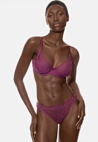 Krajkové lingerie v hluboké mauve s květinovými vzory; podprsenka má nastavitelné ramínka a kalhotky mají nízký střih a poloprůhlednou tkaninu.
