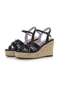 Sandali wedge neri con suola in juta intrecciata, cinturini lisci e una decorativa accentuazione a nodo. Sottopiede di un leggero colore viola con dettagli del marchio.