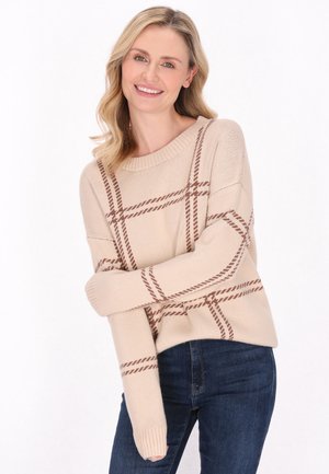 Beige trui met bruine ruitpatroon, ronde halslijn en ribgebreide manchetten. Draagt bij donkere blauwe jeans, met een relaxte pasvorm en zachte textuur.