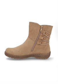 Botín de ante beige con cremallera lateral y correas elásticas decorativas, que cuenta con una suela de goma texturizada para uso exterior.