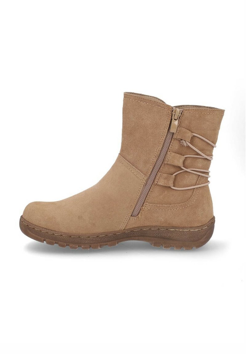 Botín de ante beige con cremallera lateral y correas elásticas decorativas, que cuenta con una suela de goma texturizada para uso exterior.