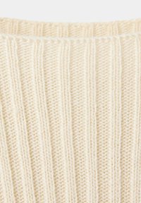 Gros plan sur un tissu tricoté de couleur crème avec une texture côtelée verticale et des détails de fibres douces.