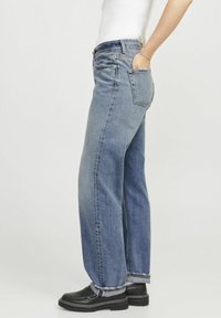 Vaqueros de mezclilla azul con un corte relajado, cintura alta y pierna ajustada. Incluyen cinco bolsillos y costuras en contraste a lo largo del dobladillo.
