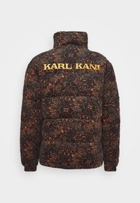Giubbotto imbottito nero con un intricato motivo paisley arancione. Logo "KARL KANI" in bold giallo sulla parte superiore della schiena.