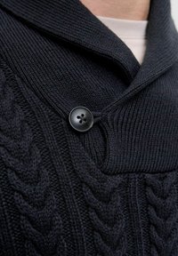Ciemnogranatowy sweter dzianinowy z kołnierzem szalowym, z teksturowanym wzorem w warkocze i jednym czarnym zapięciem na guzik.
