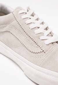 Baskets en daim gris clair avec une semelle en caoutchouc blanche et des lacets. Présentent une couture décorative le long du côté pour plus de détails.