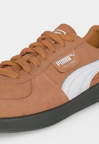 Baskets Puma Palermo marron avec lacets assortis, bande blanche Puma sur le côté et semelle noire texturée.