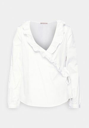 Vit blus med lång ärm, djup V-ringning och volangkrage. Har rynkade detaljer vid sidorna och elastiska ärmslut. Tillverkad av lätt tyg.