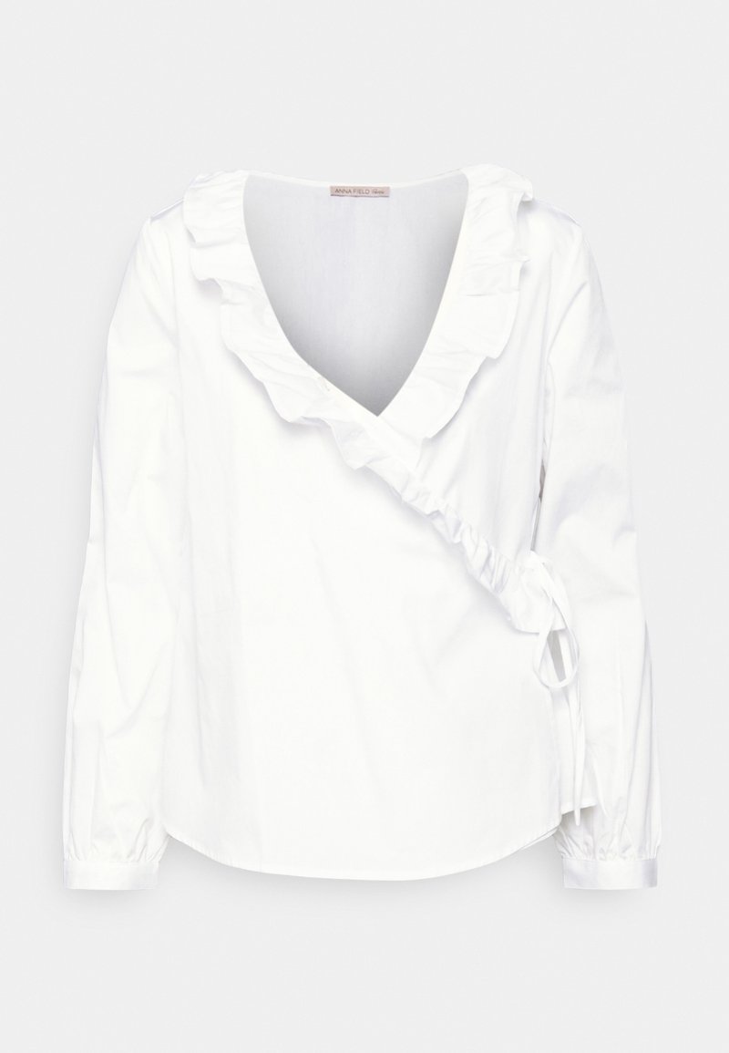 Weiße Bluse mit langen Ärmeln, tiefem V-Ausschnitt und Rüschensaum. Mit gerafft Details an der Seite und elastischen Manschetten. Aus leichtem Stoff gefertigt.