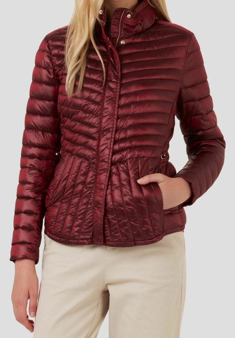 Doudoune bordeaux avec matelassage horizontal et vertical, col montant, fermeture éclair et poches. Tissu en nylon lisse et brillant.