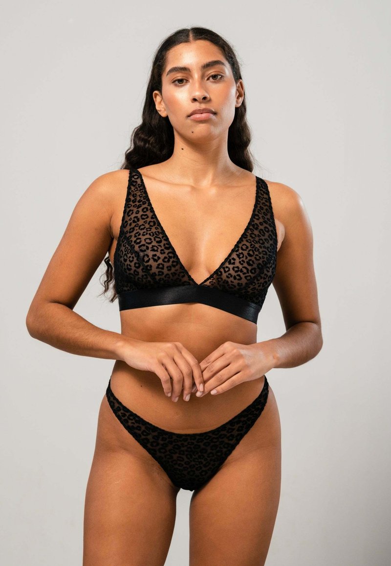 Schwarze Leopardenmuster-Bralette mit tiefem V-Ausschnitt und dünnen Trägern, kombiniert mit passendem Tanga. Durchsichtiges Material mit Satinakzenten.