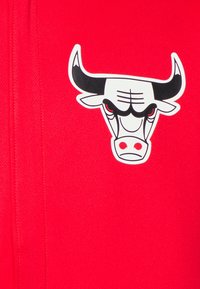 Red fabric features a prominent black and white bull logo with notable details like the eyes and horns, enhancing the bold design.