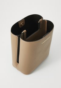 Tan leren handtas met een gestructureerd ontwerp, goudkleurige hardware en een contrasterende zwarte binnenkant. Voorzien van drukknoopsluiting en een gladde textuur.