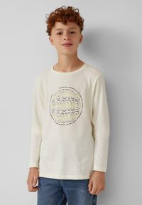 Creme kleurige longsleeve shirt met een circulaire grafiek waarop het woord "SOUND" staat in vetgedrukte zwarte en gele letters. Zachte stof, relaxed fit.