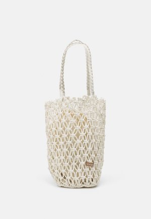 Sac fourre-tout tissé blanc avec un design en maille, doté de deux poignées tressées et d'une étiquette marron avec du texte. Structure légère et ouverte.