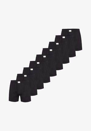 Schwarze Baumwollboxershorts mit einem elastischen Bund, mit einer Knopfleiste vorne, in einer Reihe angeordnet, die mehrere Stücke zeigt.