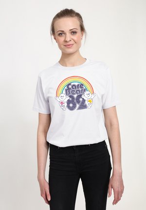 Bílý bavlněný tričko s barevnou grafikou duhy a textem "Care Bears 82" spolu s ilustracemi kreslených medvídků. Krátké rukávy, kulatý výstřih.