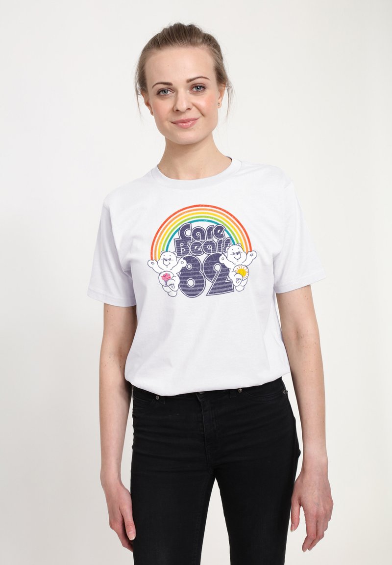 Bílý bavlněný tričko s barevnou grafikou duhy a textem "Care Bears 82" spolu s ilustracemi kreslených medvídků. Krátké rukávy, kulatý výstřih.