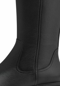 Botte en cuir noir avec une finition texturée, des coutures renforcées et une silhouette élégante et lisse. Aucun matériel ou accent visible.