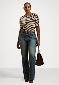 Brun og krem zebra-stribede kortærmet top, parret med blå lige ben jeans og brun håndtaske. Glat stoftekstur, afslappet pasform.