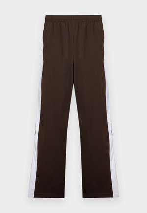 Καφέ φόρμες με λευκές πλαϊνές ρίγες και ελαστική μέση, παρουσιασμένες σε απλό φόντο.