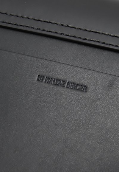 Sac en cuir noir avec un texte en relief "BY MALENE BIRGER" et une surface légèrement texturée avec des détails de couture contrastants.