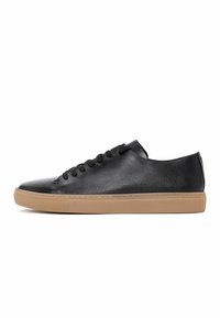Sneaker in pelle nera con profilo basso, superficie texturizzata, punta rotonda, lacci neri e suola in gomma beige a contrasto.