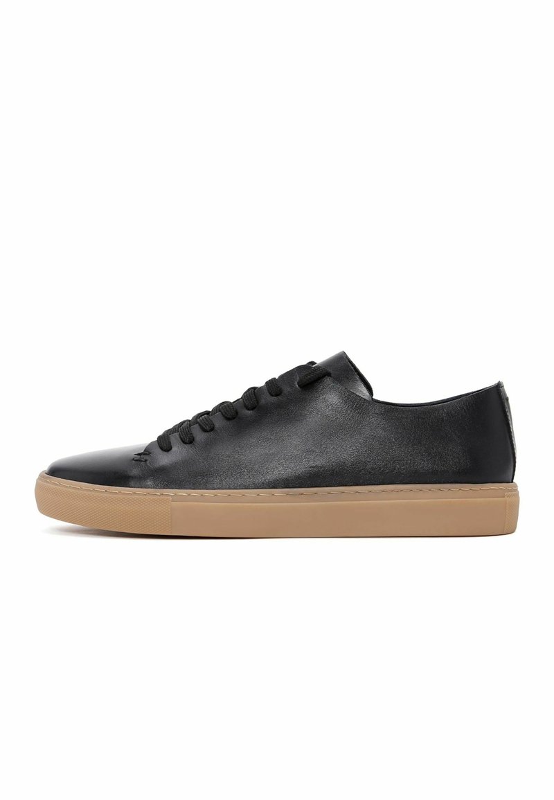Sneaker in pelle nera con profilo basso, superficie texturizzata, punta rotonda, lacci neri e suola in gomma beige a contrasto.