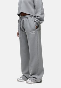 Grijze cropped sweatshirt en wijde sweatpants met "GOOD FOR Nothing" geborduurd in het wit. Zachte stof met een elastische tailleband.
