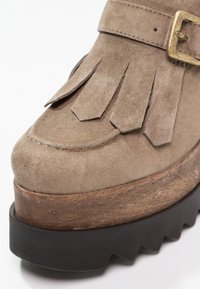 Bottines à plateforme en daim brun clair, dotées d'accents à franges, d'une semelle intermédiaire en bois épaisse et d'une semelle extérieure en caoutchouc noir texturé.