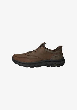 Bruine leren sneaker met zwarte rubberen zool, ronde neus, vetersluiting, gewatteerde kraag en Goodyear branding. Geweven oppervlak en gestikte accenten.