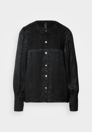 Svart bluse med et teksturert leopardmønster, som har en rund krage med blomsterdetaljer og firkantede knapper foran. Lange ermer.