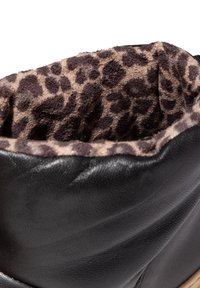 Bota de cuero negro con un suave forro de tela con estampado de leopardo visible en la parte superior.