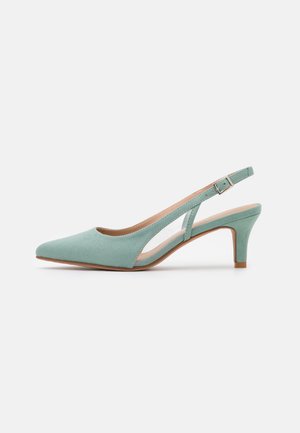 Lichtgroene suède slingback pump met puntige neus, verstelbare gespsluiting en smalle hak van gemiddelde hoogte op witte achtergrond.