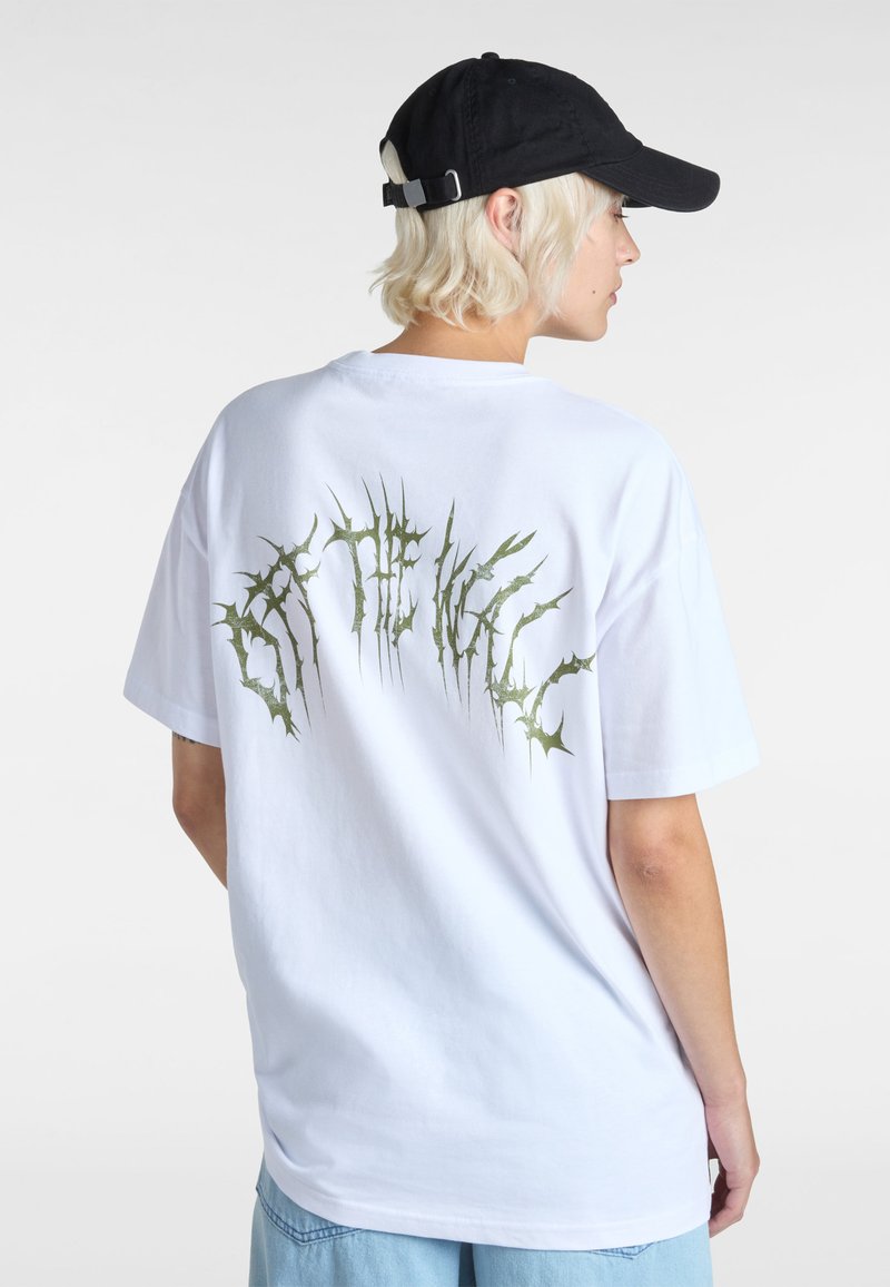 Hvid bomulds t-shirt med et stort grønt tornlignende grafisk design på ryggen. Løs pasform med korte ærmer og rund halsudskæring.