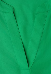 Tissu vert avec un décolleté en V profond orné de détails de coutures le long des bords du col.