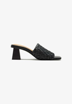 Mule en cuir tressé noir avec un bout carré, caractérisé par un dessus texturé et un talon bloc épais et angulaire.