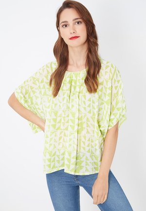 Blusa verde lima hecha de tela liviana, con un patrón geométrico de triángulos y un ajuste suelto y fluido con mangas anchas.